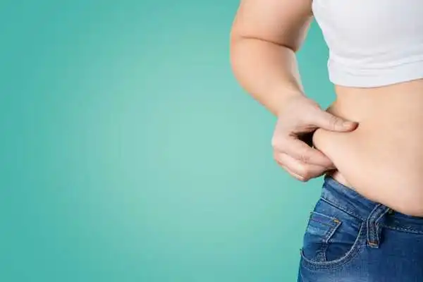 Image of woman pinching her love handles to show weight gain Wootton Bassett