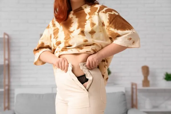 Image of woman trying to do her trousers up after pregnancy weight gain Wootton Bassett