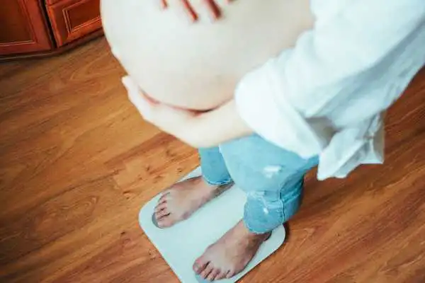 Image of woman weighing herself and experiencing weight gain through pregnancy Wootton Bassett